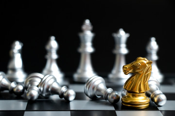 Gold horse in chess game face with the another silver team on black background (Concept for company strategy, business victory or decision)
