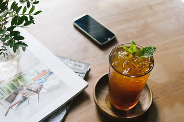 Iced lavender tea with smartphone and magazine on the wooden table.