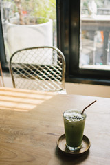 Iced milk green tea on wooden table in the cafe.