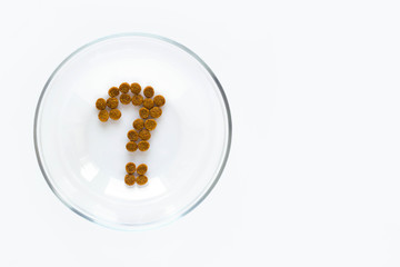 Question mark made of dry cat or dog food in bowl on white background. Concept of choosing a dry food for pet.
