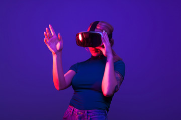 Hot sexy woman wearing a VR head set on blue background with red light from aside