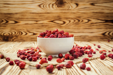 red strawberries in bowl on a wooden background