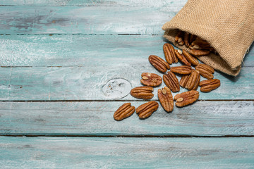 Pecan in burlap bag on wooden background . Healthy food