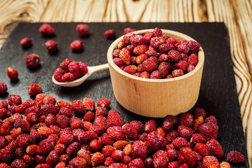 red strawberries in bowl on a wooden background