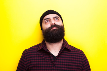 Bearded hipster wearing a hat on yellow background in studio photo