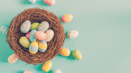 Colorful easter egg and nest on green pastel color background with space.