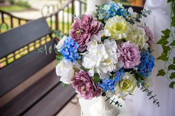Wedding arch decorated with flowers, white chairs and flowers bouquet