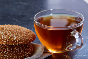 Shallow depth of field photo of a glass cup of black tea with brownies on a dark greyish marble background.