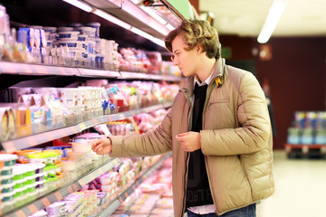 Man shopping in supermarket, reading product information