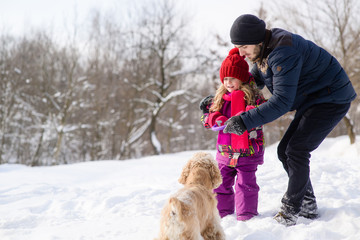Obraz premium Father and daughter train their dog during winter walk