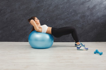 Fitness woman working on her abs with fitness ball indoors