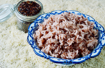 cooked Riceberry mixed with white rice and uncooked Rice on background