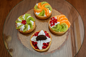 four tartlets with cream, biscuits and fruits