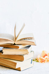 a stack of old battered books, and upstairs, an open book on a white background, copyspace