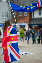 Female Brexit protestor European demonstration with UK flag and EU banner in typical English high street during protest march