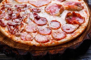 Delicious yummy fresh pizza with bacon, salami, ham and pepperoni and appetizing crust, close up. Italian food, pizzeria concept
