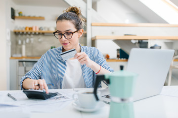 Young woman paying bills online with credit card 