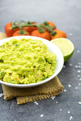 Bowl of guacamole on black wooden background.