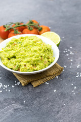 Bowl of guacamole on black wooden background.
