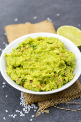 Bowl of guacamole on black wooden background.