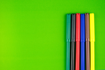 Fototapeta premium A set of different colors of felt-tip pens on a green background.