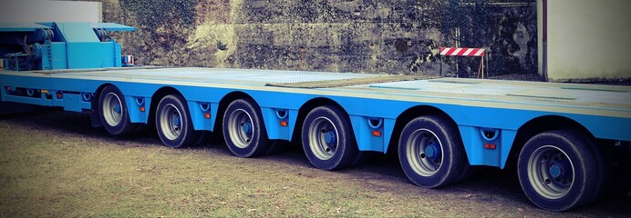 very long blue truck with six  axles of wheels with vintage effect