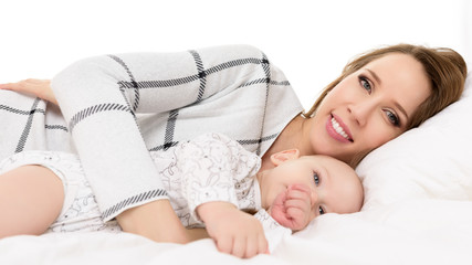 Happy young smiling mother and her baby son lying on a bed together. Happy family. Mother and newborn child portrait.