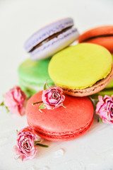 Delicate Fresh Colorful French Macaroons In Pastel Colors With Flowers Roses On A Light Textile Background