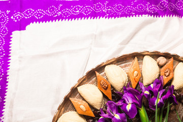 Novruz copper tray with Azerbaijan national pastry pakhlava and shekerbura with purple fleur de lis flowers on white traditional kelagai silk female scarf background, spring new year celebration 