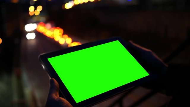 Watching a green screen tablet near a highway at night