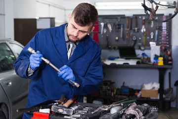Male worker is choosing instruments for repair car