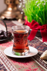 Novruz setting table decoration, tea in  tulip shape glass on ethnic motives rustic table cloth with wheat grass, dyed eggs, traditional sweets, samovar, new year sring celebration, nature awakening