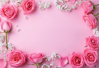 Fototapeta na wymiar Rose flowers frame on pink background. Top view. Copy space