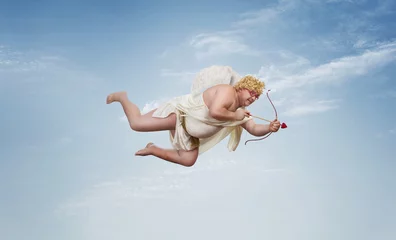Foto op Canvas Funny overweight cupid aiming with the arrow of love over clear blue sky with copy space © rangizzz