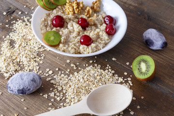 Cooked and raw oatmeal with fruit on a wooden background