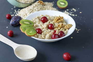 Cooked and raw oatmeal with fruit on a dark background