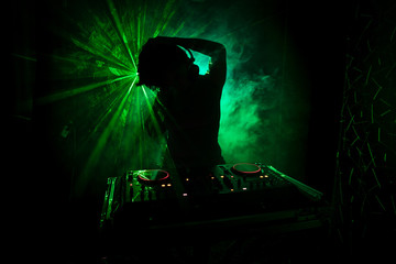 DJ Spinning, Mixing, and Scratching in a Night Club, Hands of dj tweak various track controls on...