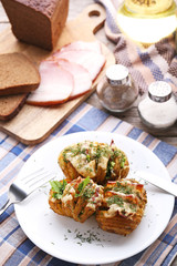 Baked potato with cheese and bacon in plate with fork and knife