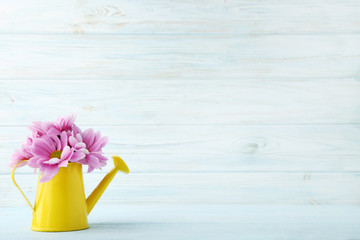 Watering can with pink flowers on wooden table