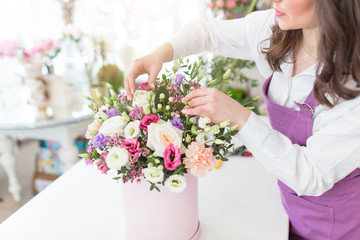 Young happy florist making fresh flowers arrangement in gift box for a holidays