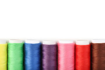 Colourful thread spools on white background