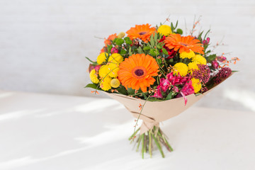 Naklejka premium Fresh and lush bouquet of colorful flowers, on white brick background with copyspace