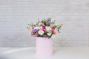 Bouquet of different flowers for holidays on white table with brick wall background, copy space