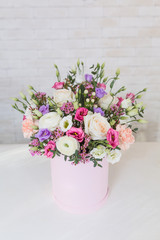 Fresh and lush bouquet of colorful flowers, on white brick background with copyspace