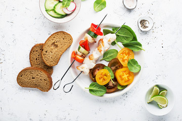 Skewers with chicken fillet, capsicum, zucchini, champignons and fresh colored tomatoes, spinach, cucumber, radish. Top view