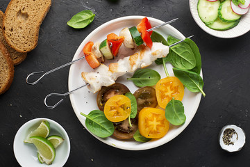 Skewers with chicken fillet, capsicum, zucchini, champignons and fresh colored tomatoes, spinach, cucumber, radish. Top view
