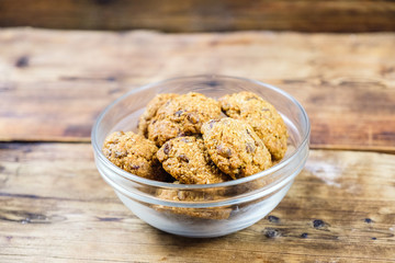 Homemade oatmeal cookies with raisins in glass plate on wooden background. Side view.