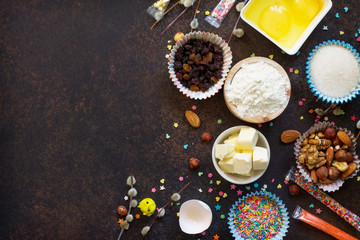 Ingredients for Easter baking - eggs, nuts, flour, yeast, butter, raisins, sugar and willow branches. Seasonal, food background. Flat lay. Top view with copy space.