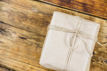 Close-up gift wrapped kraft paper on wooden background. Left on photo.