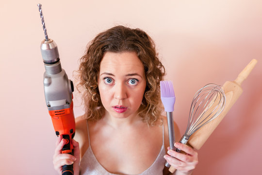 Beautiful curly woman holding man driller and kitchen tools. Gender equality, women's day concept.